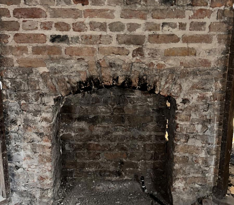 destroyed and broken fireplace inside an abandoned home